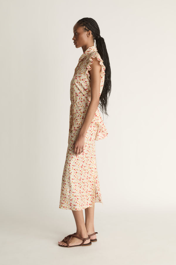Woman wearing a floral blouse and skirt on a plain background