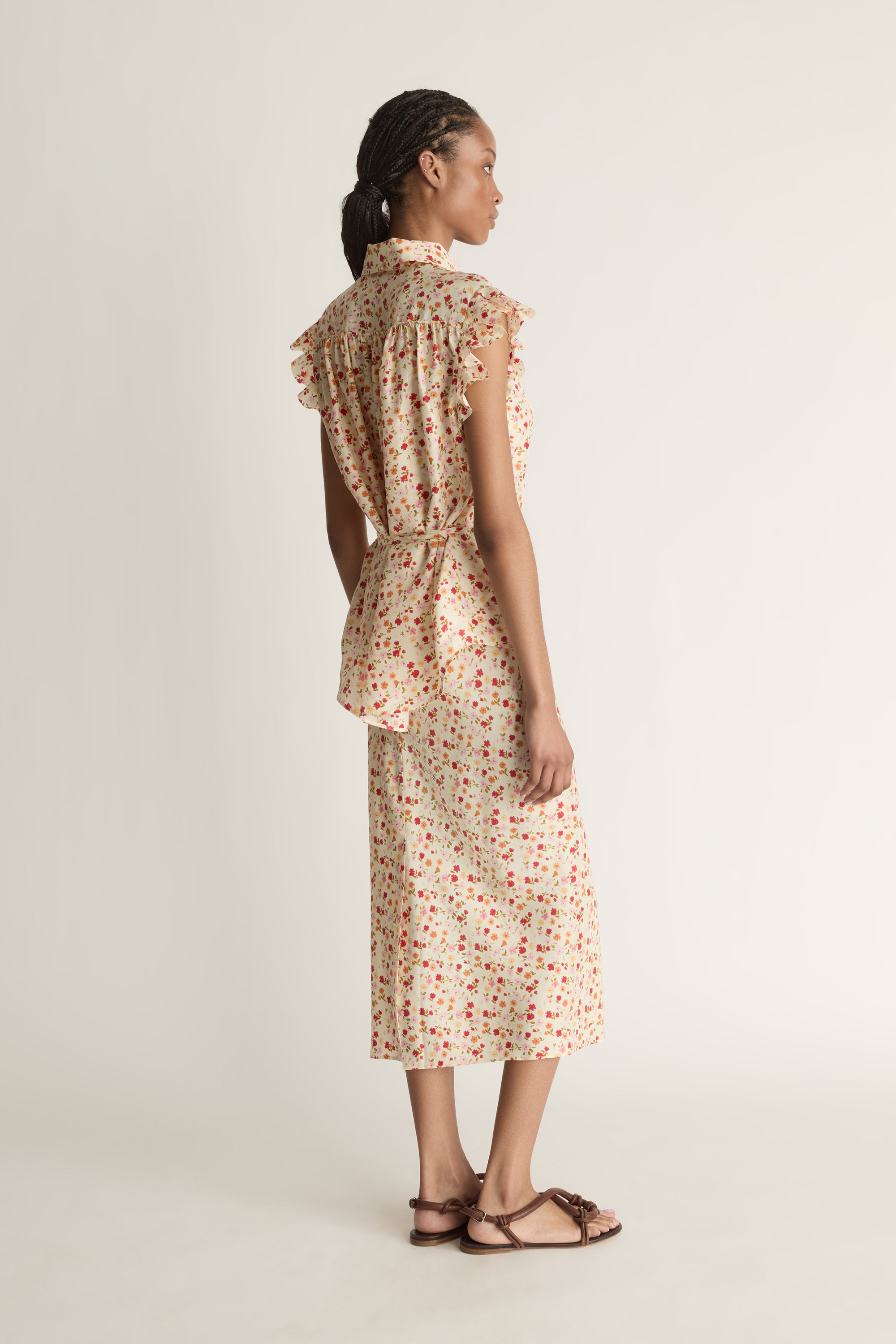 Woman wearing a floral blouse and skirt on a plain background
