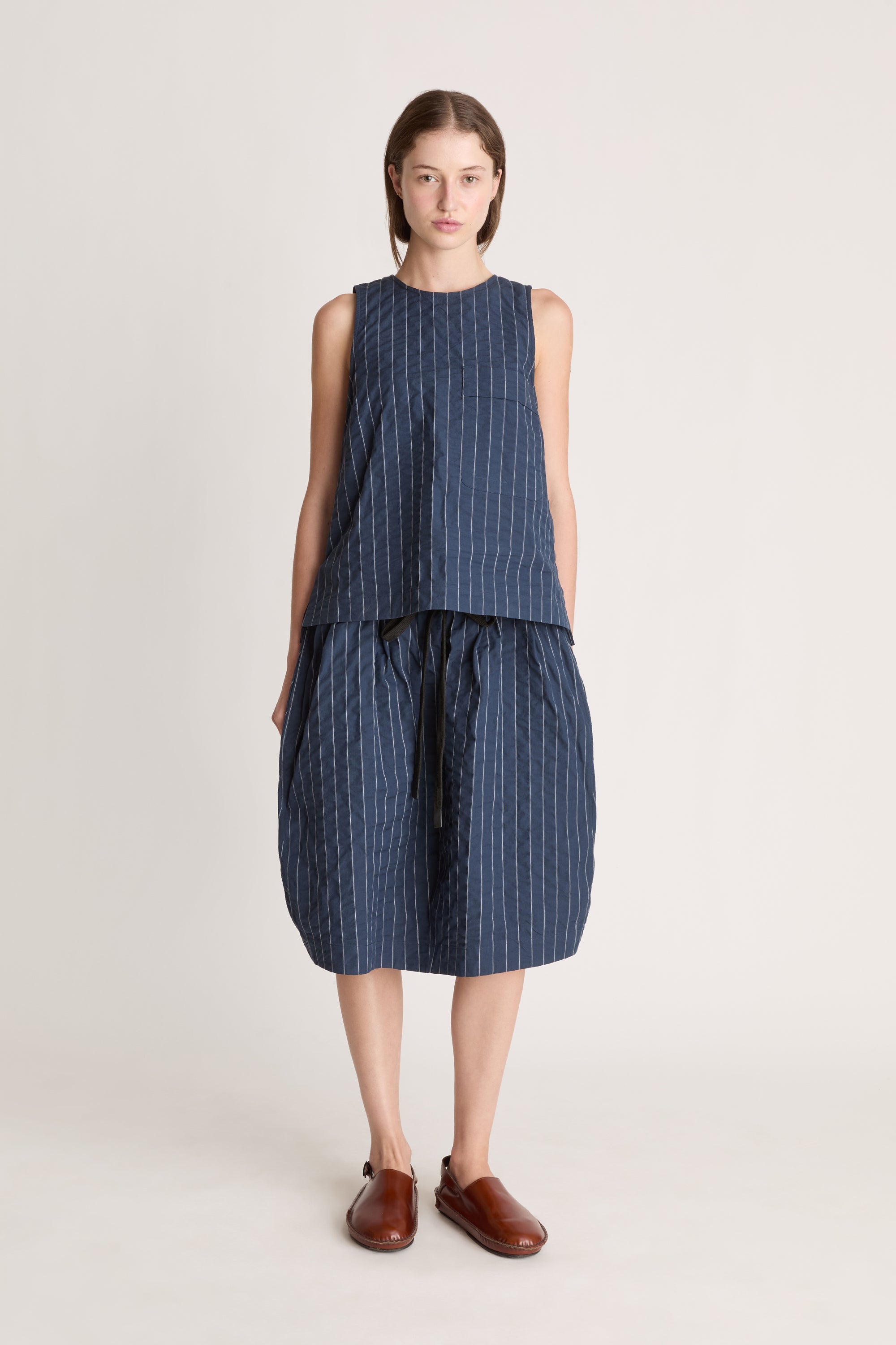 A woman wearing a blue striped top and skirt on a white background