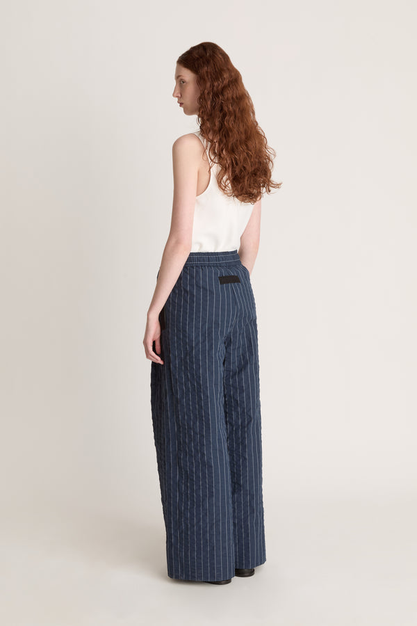 Woman wearing a white top and blue striped pants on a white background