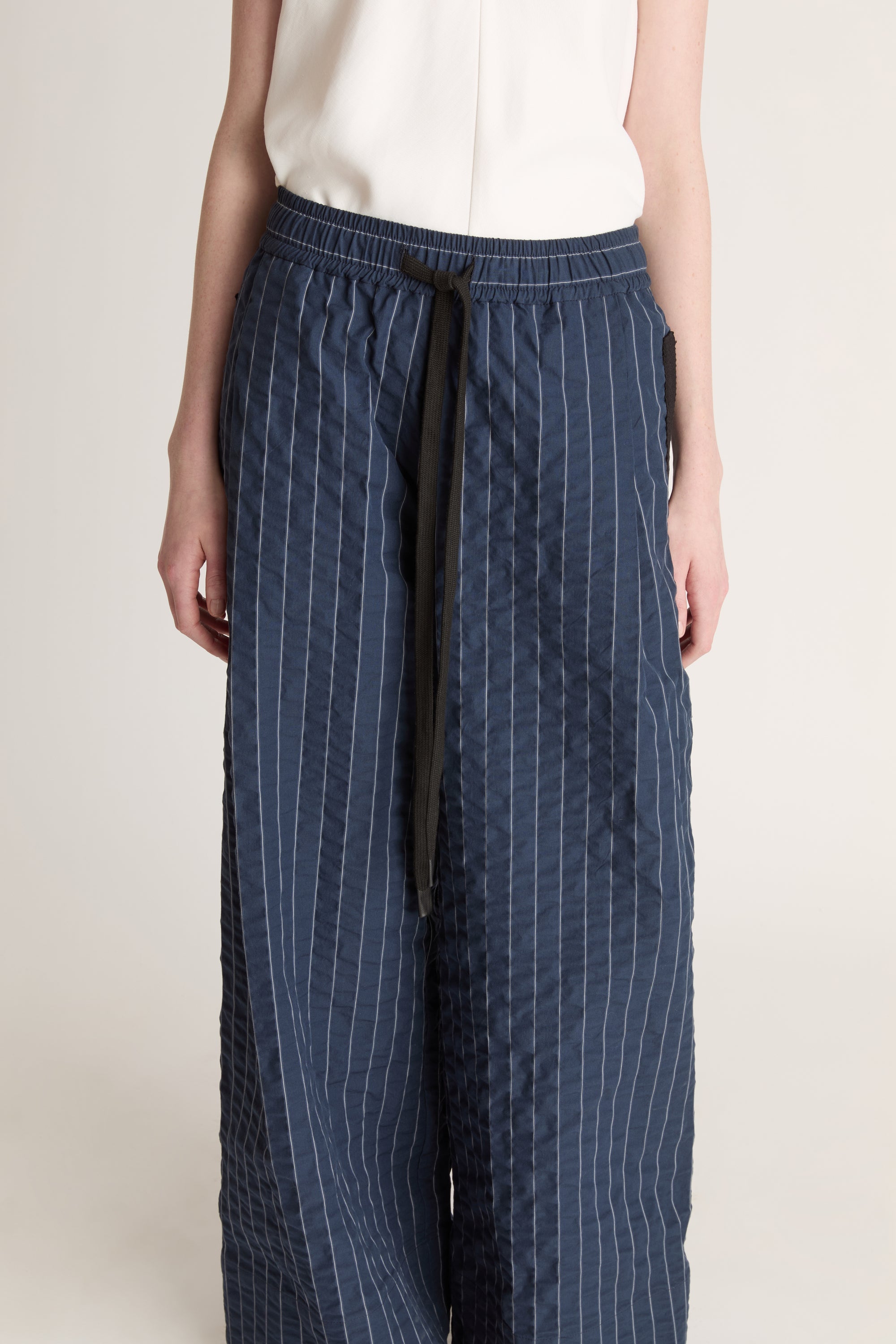 Woman wearing a white top and blue striped pants on a white background