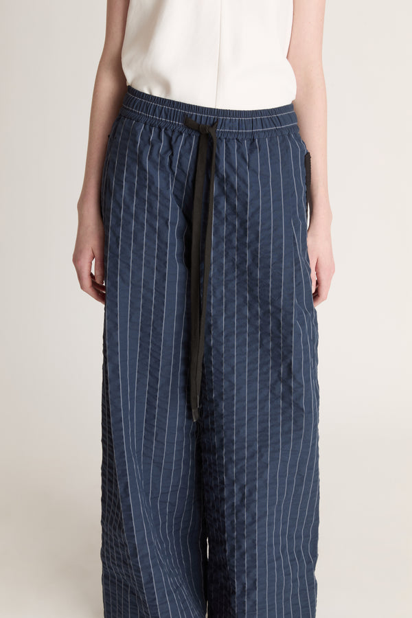 Woman wearing a white top and blue striped pants on a white background