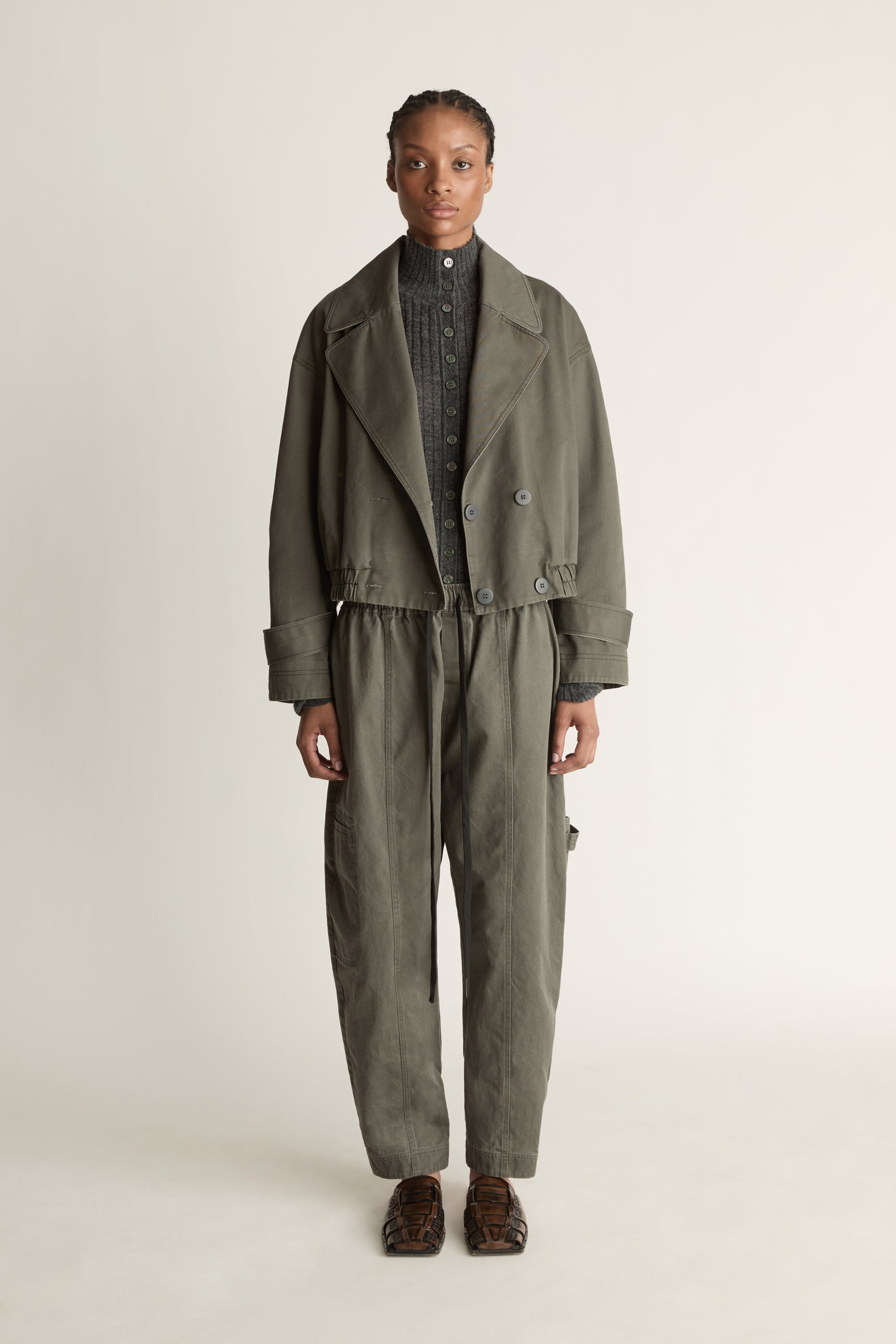 Person wearing a green coat and pants on a plain background