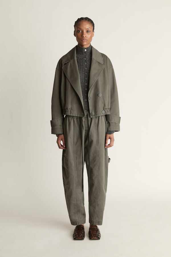 Person wearing a green coat and pants on a plain background