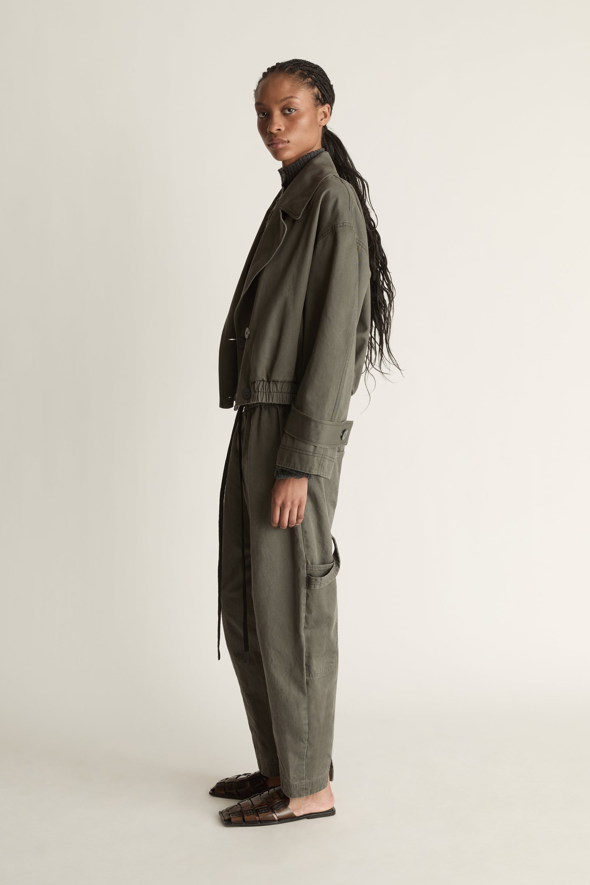 Person wearing a green coat and pants on a plain background