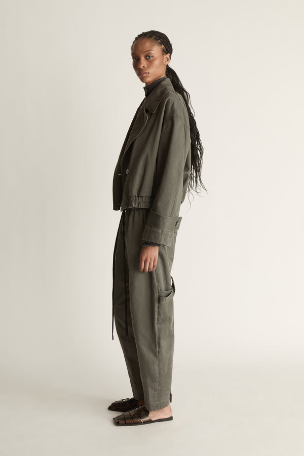 Person wearing a green coat and pants on a plain background