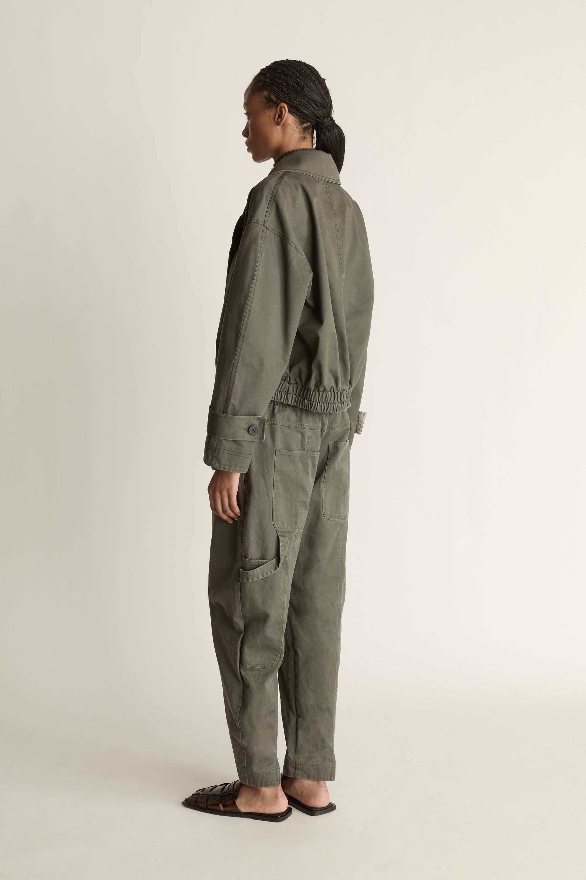 Person wearing a green coat and pants on a plain background