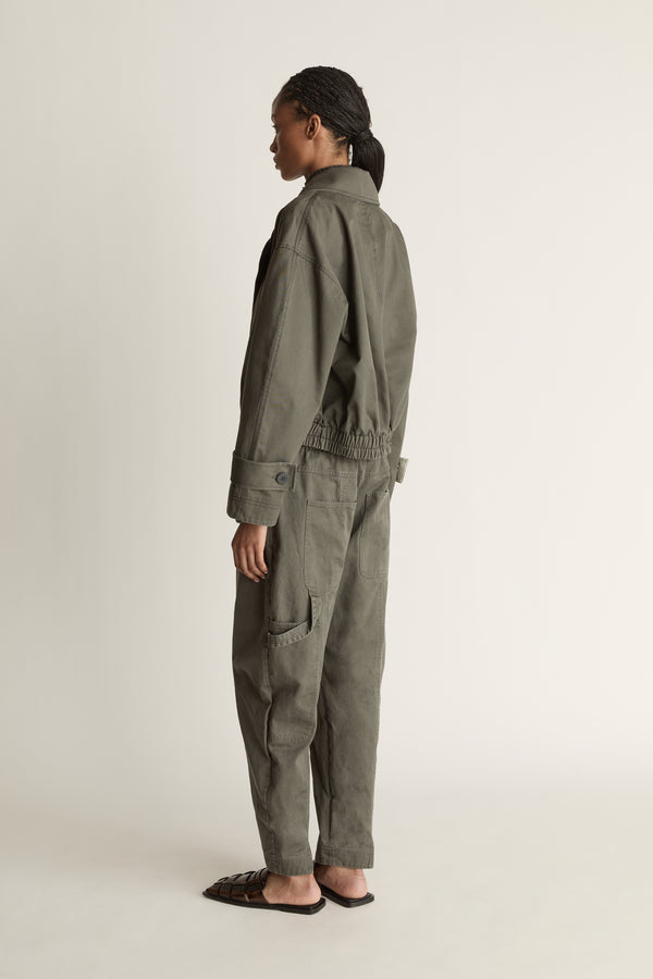 Person wearing a green coat and pants on a plain background
