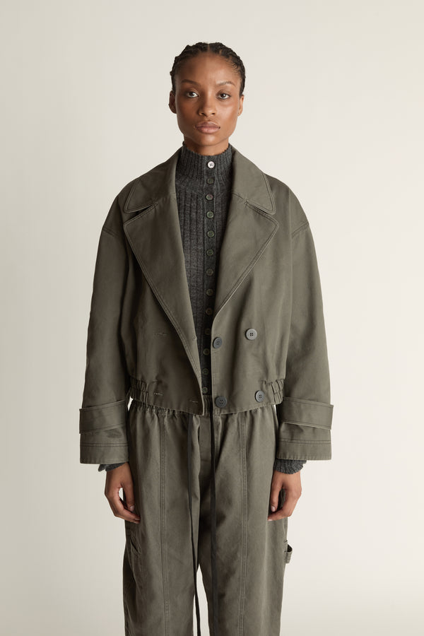 Person wearing a green coat and pants on a plain background