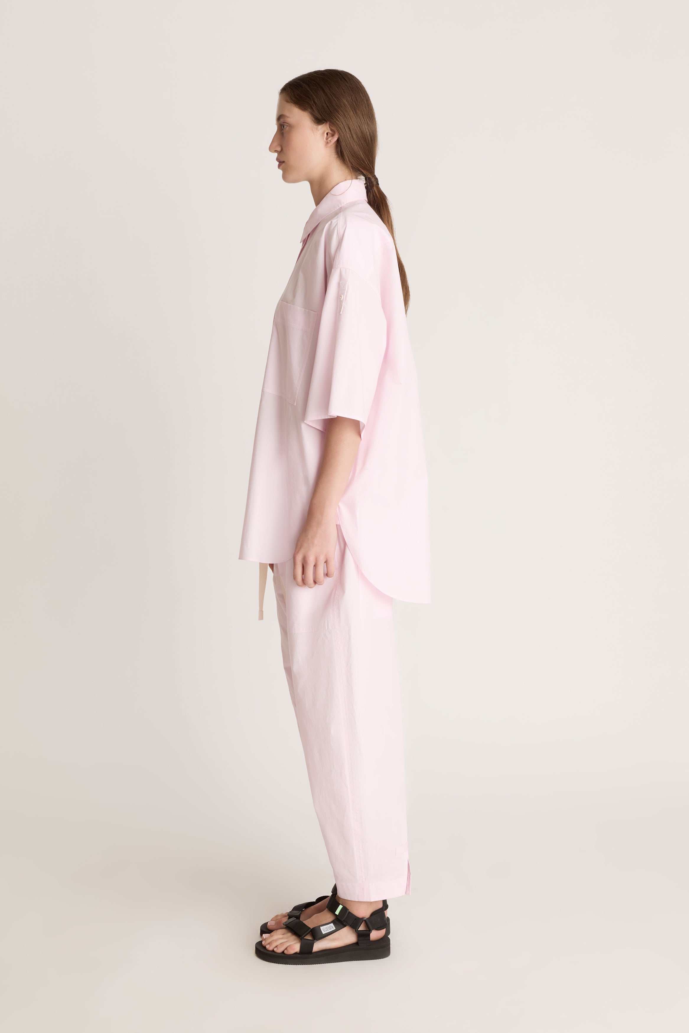 Person wearing a light pink shirt and pants on a white background