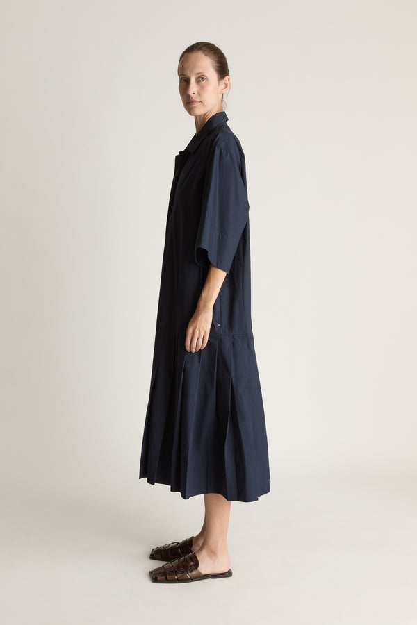 Woman wearing a navy blue dress on a plain background
