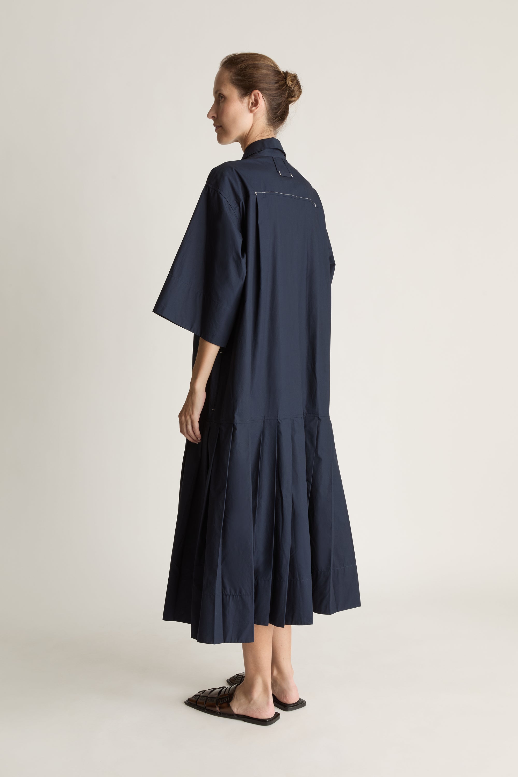 Woman wearing a navy blue dress on a plain background