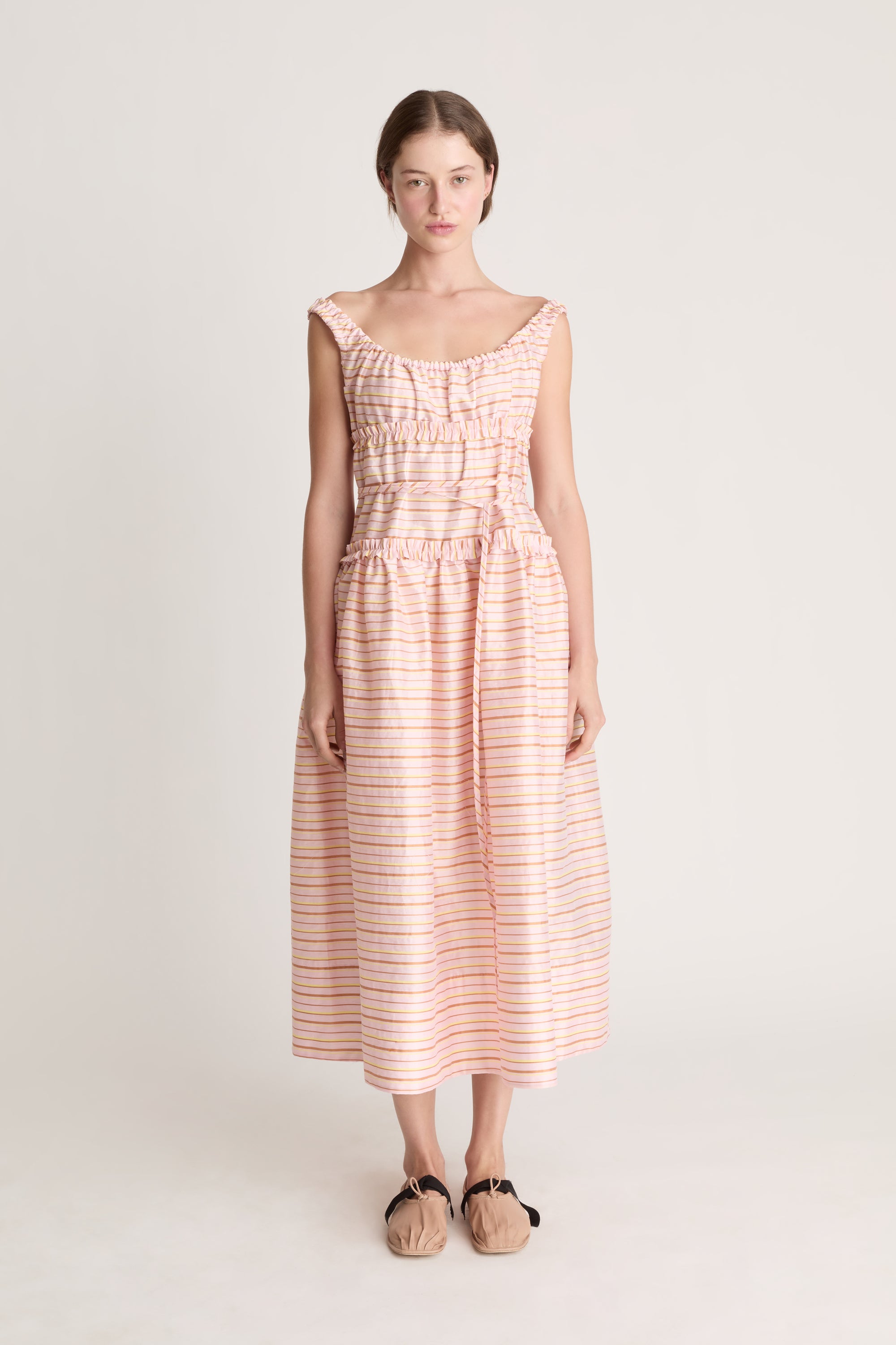 Woman wearing a sleeveless dress with a striped pattern on a plain background