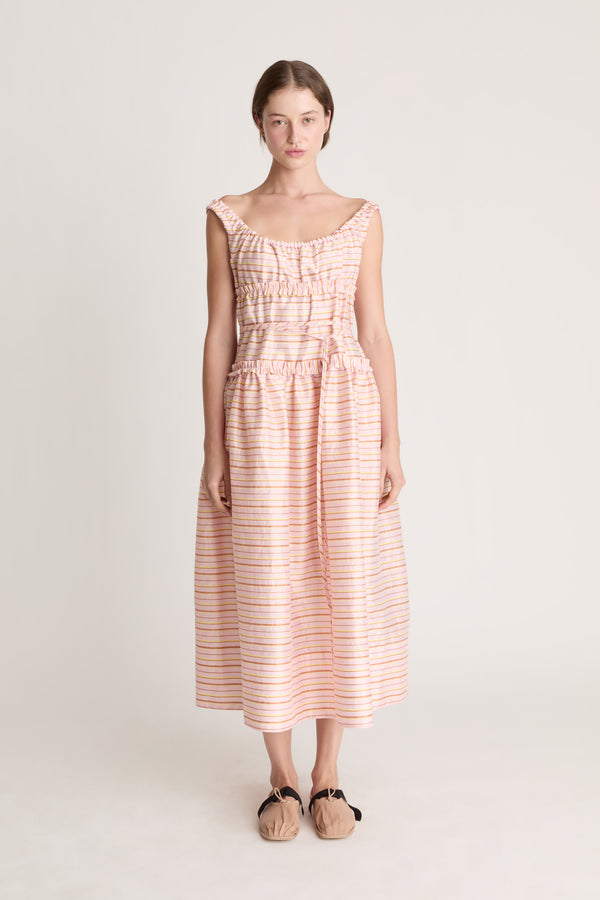 Woman wearing a sleeveless dress with a striped pattern on a plain background