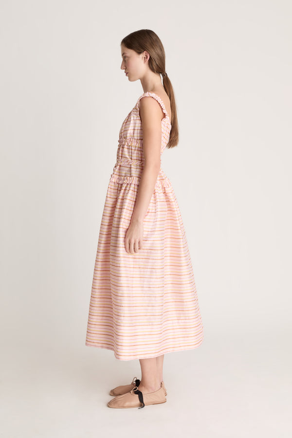 Woman wearing a sleeveless dress with a striped pattern on a plain background