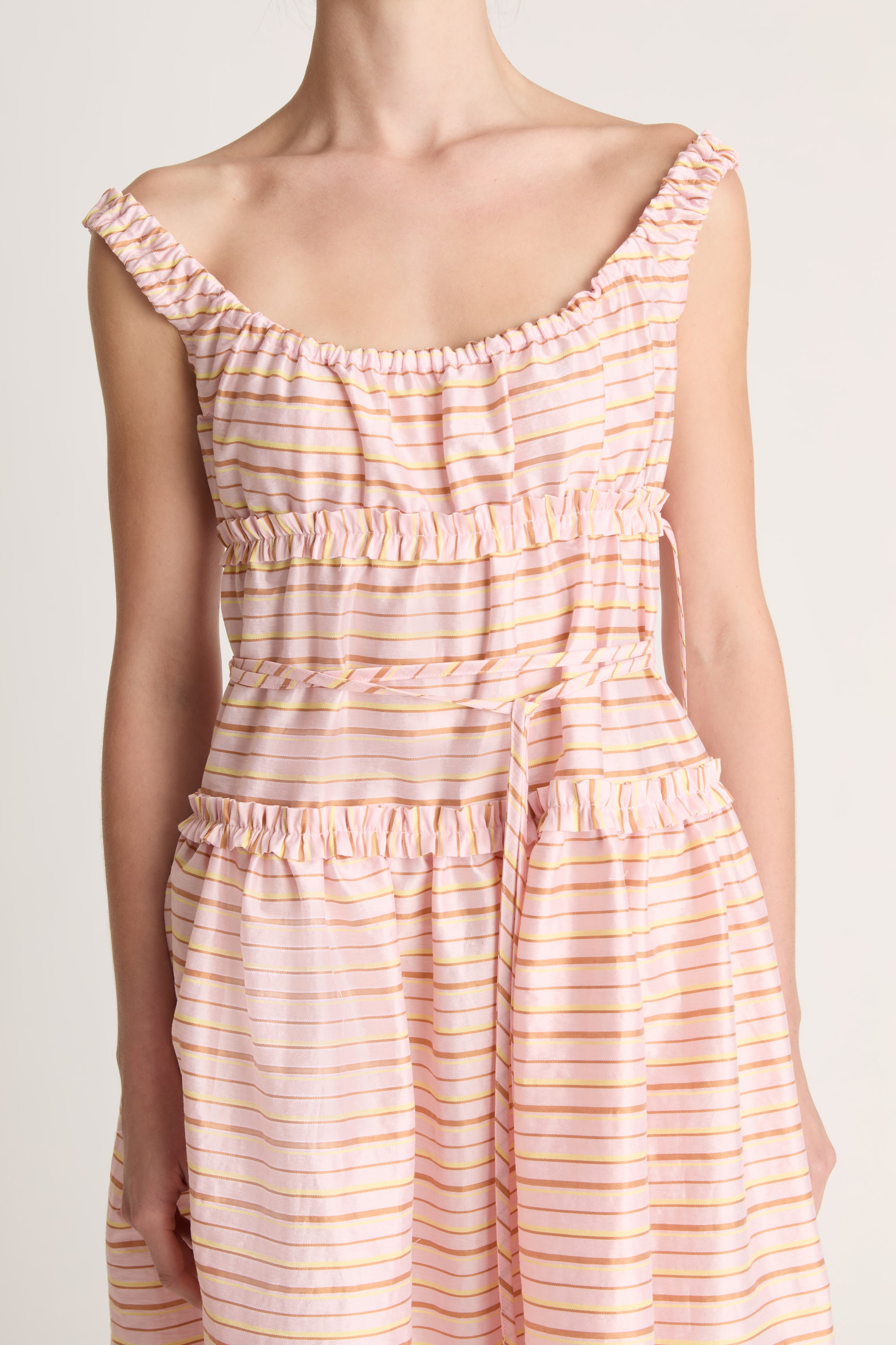 Woman wearing a sleeveless dress with a striped pattern on a plain background