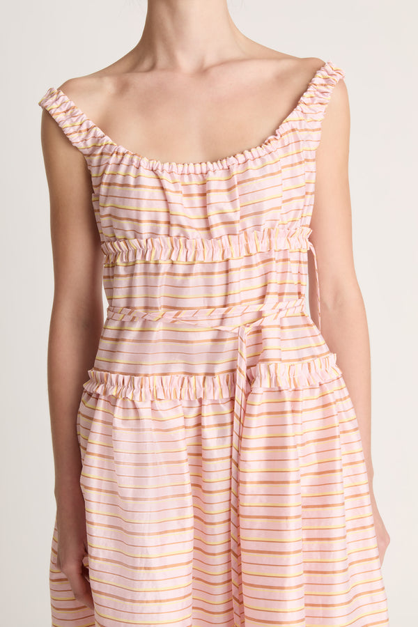 Woman wearing a sleeveless dress with a striped pattern on a plain background