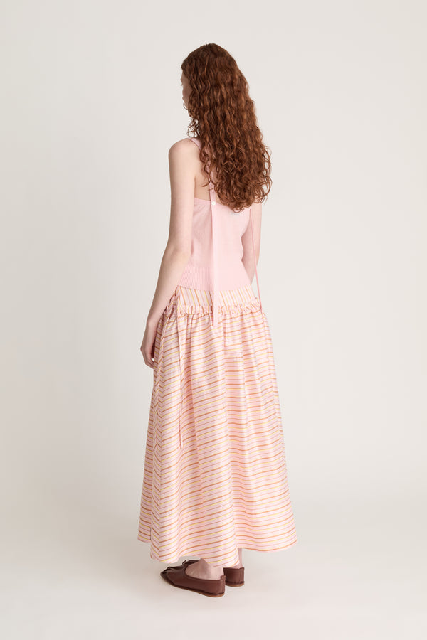 Woman wearing a pink knit cami and a pink striped skirt on a white background