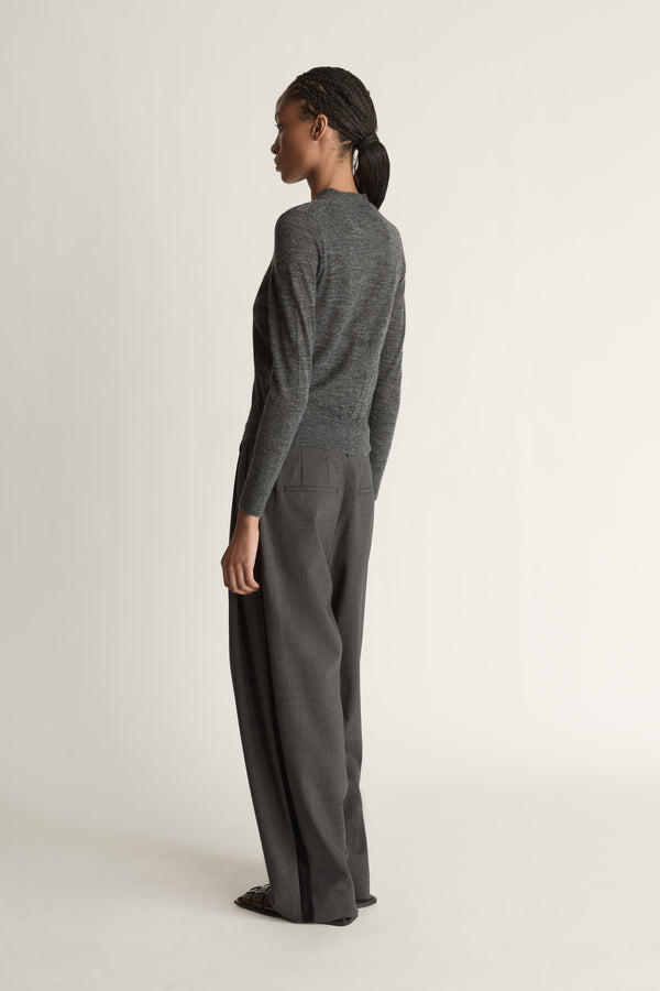 Woman wearing a grey cardigan and grey trousers on a white background