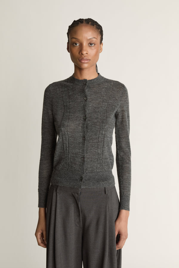 Woman wearing a grey cardigan and grey trousers on a white background