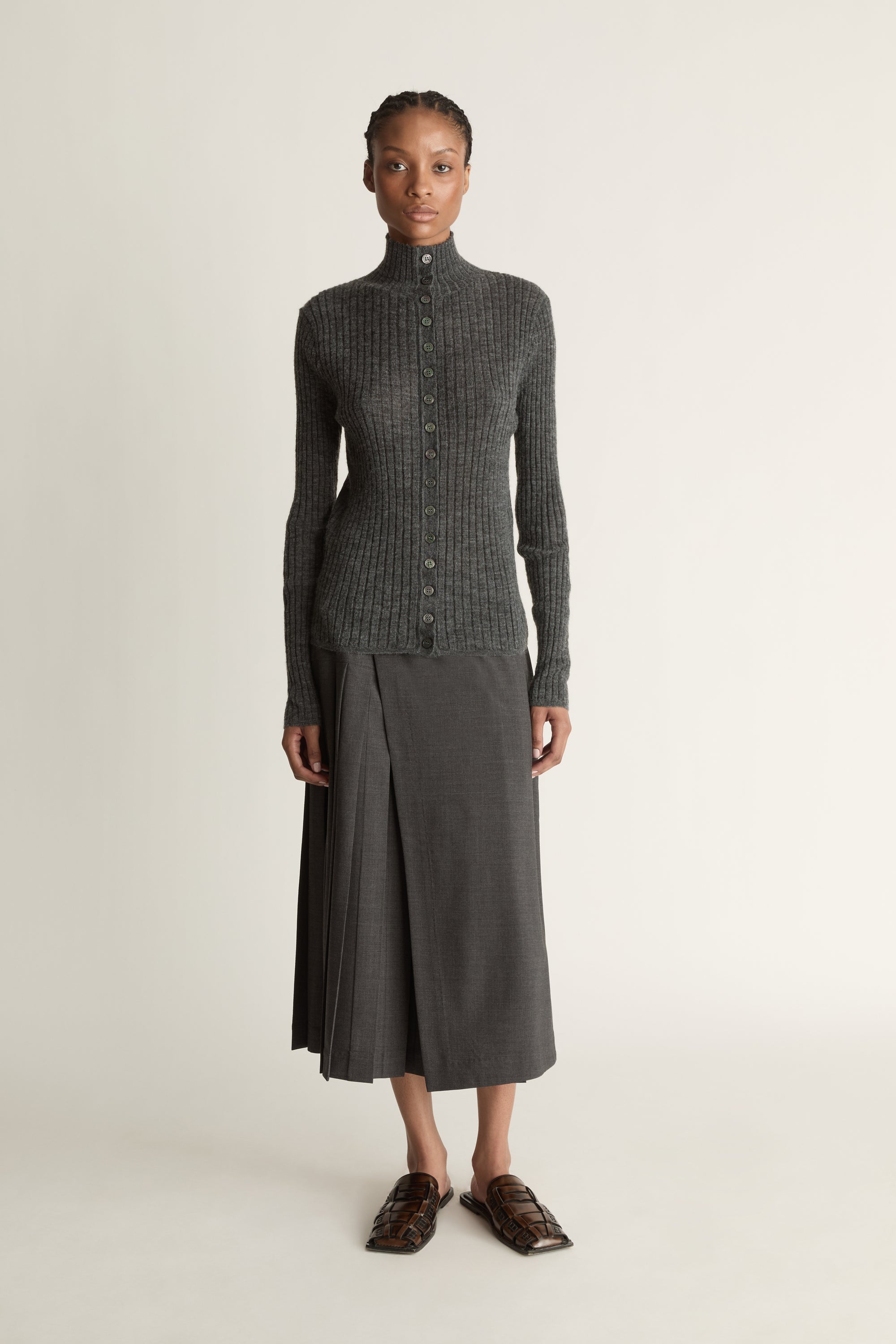 Woman wearing a gray ribbed sweater and skirt on a white background