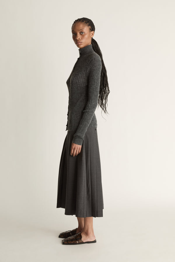 Woman wearing a gray ribbed sweater and skirt on a white background