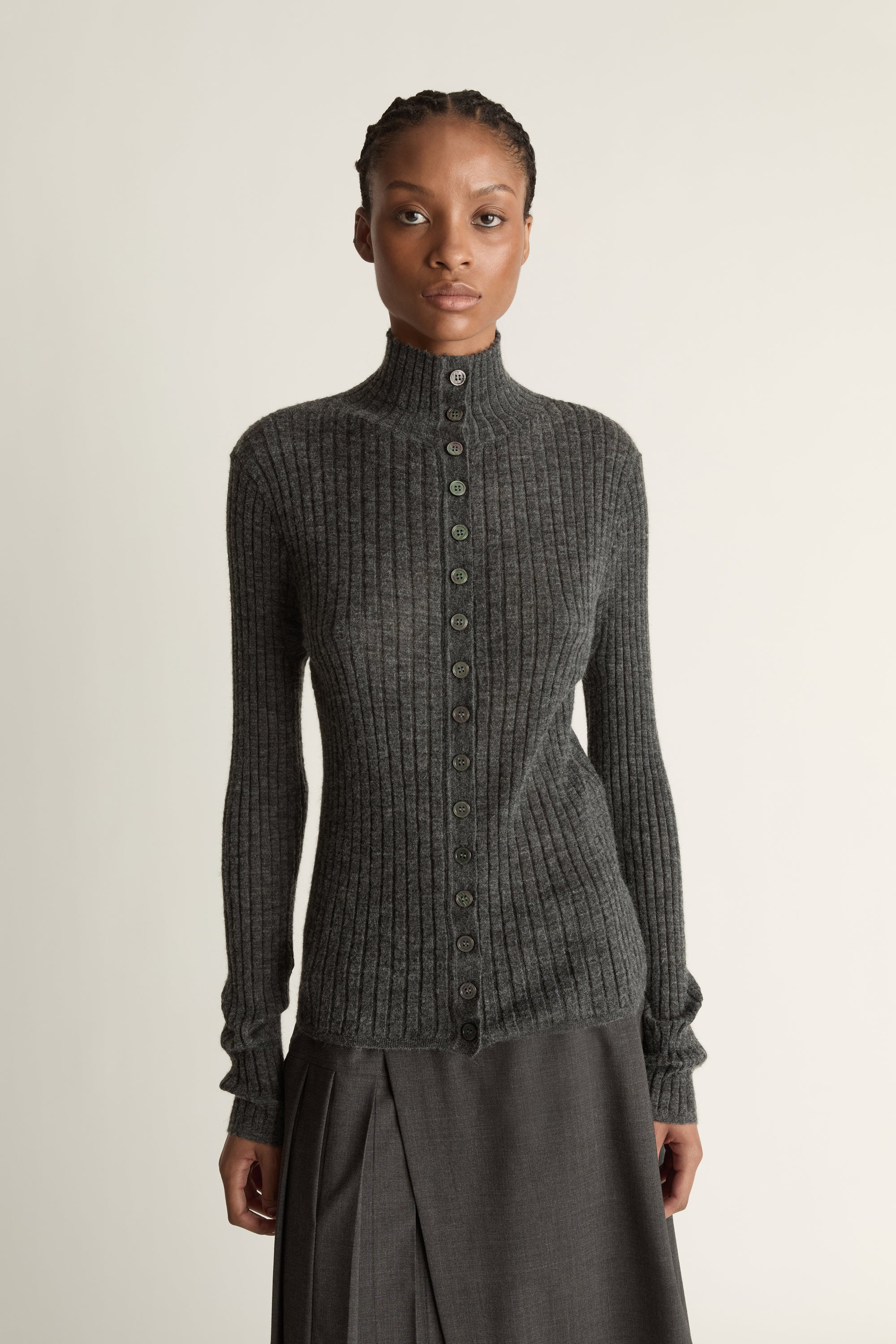 Woman wearing a gray ribbed sweater and skirt on a white background