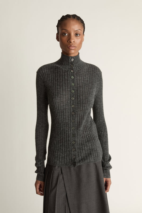 Woman wearing a gray ribbed sweater and skirt on a white background