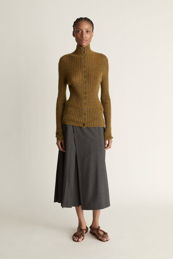 Woman wearing a brown ribbed sweater and gray skirt on a beige background