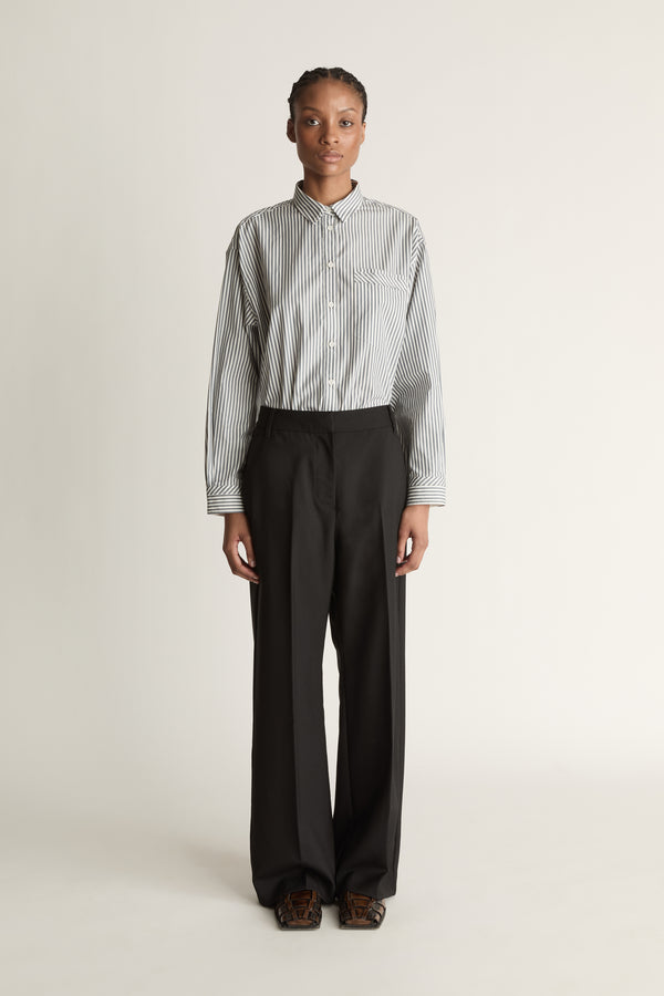 Person wearing a striped shirt and black pants on a white background