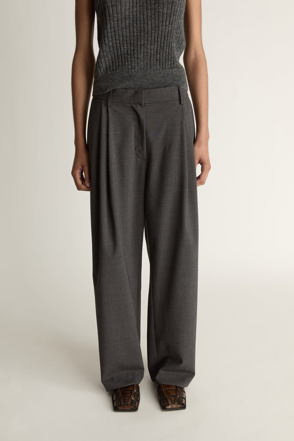 Woman wearing a sleeveless knitted top and wide-leg pants on a plain background