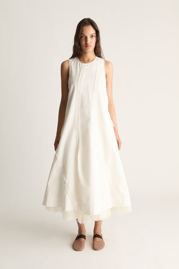 Front view of a woman wearing a white sleeveless A-line midi dress against a white studio background