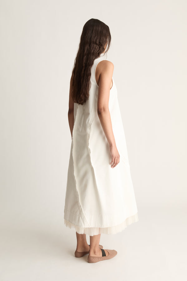 Back view of a woman with long dark hair in a white sleeveless A-line midi dress with tulle hem