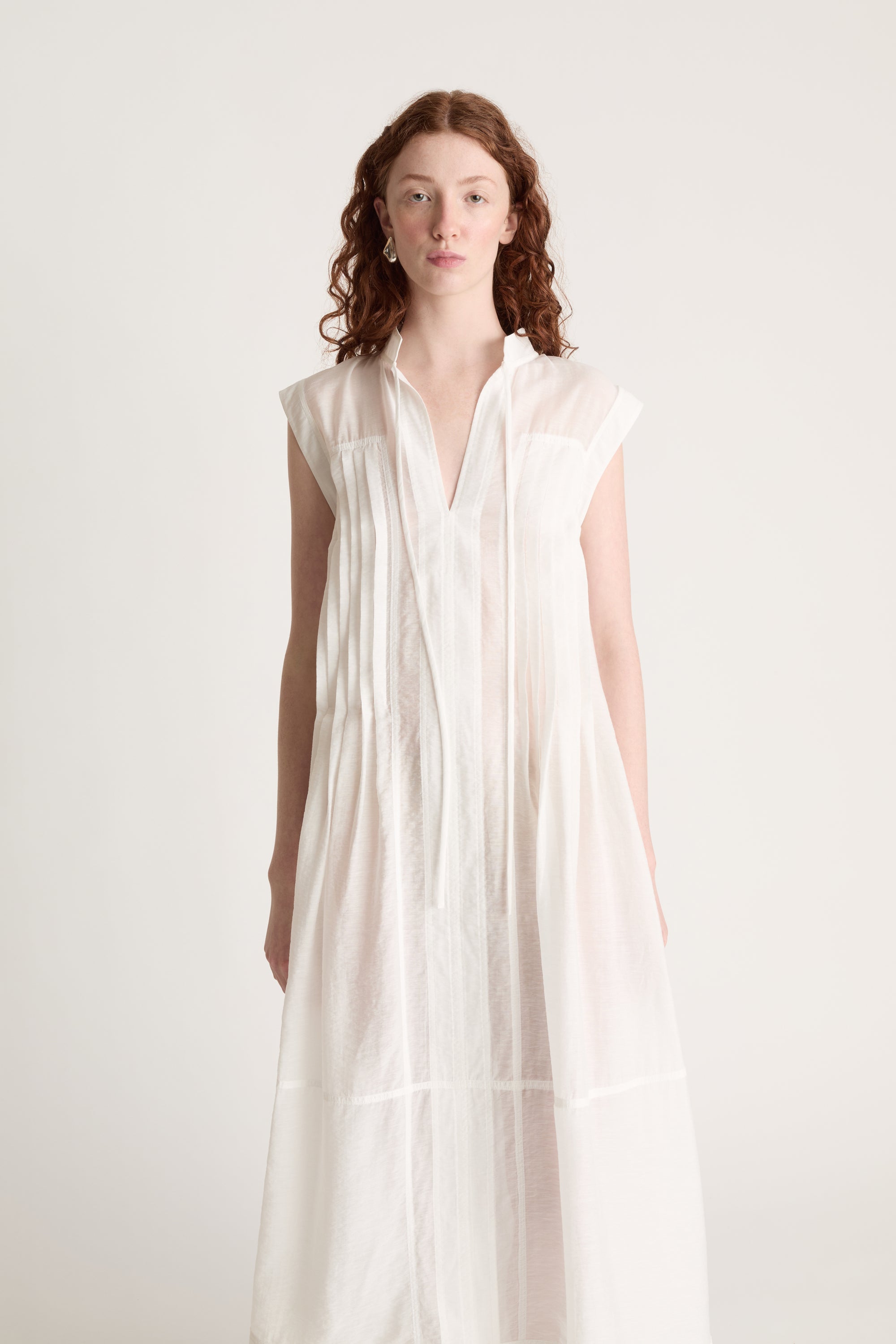Woman wearing a long white dress with brown shoes on a white background