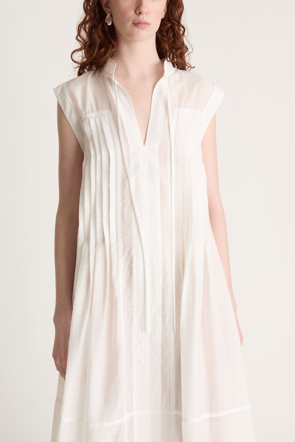 Woman wearing a long white dress with brown shoes on a white background