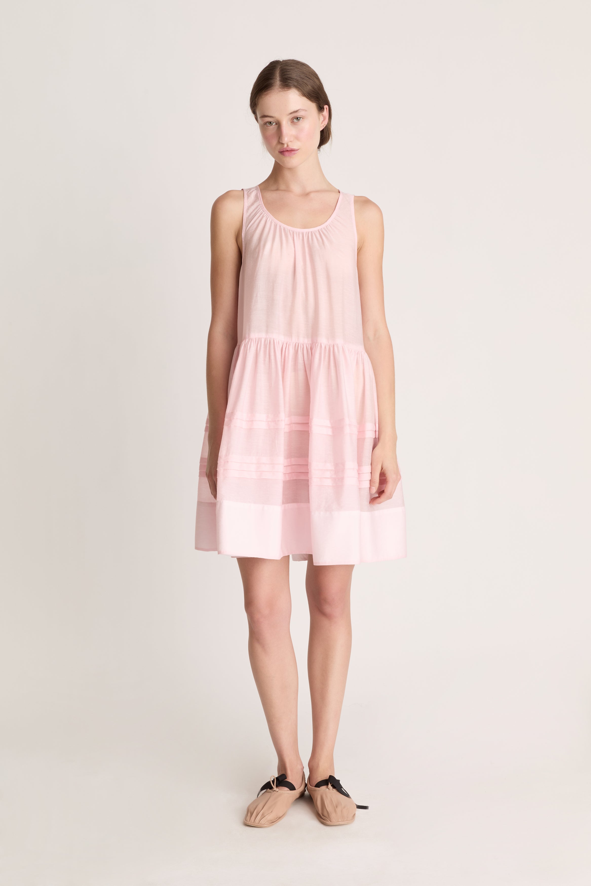 Woman wearing a light pink sleeveless dress on a white background