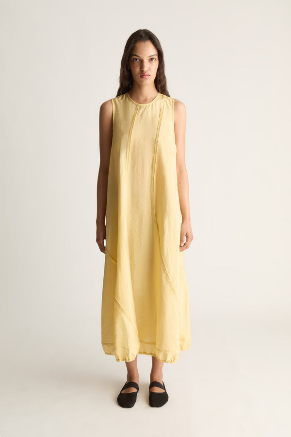 Front view of a woman wearing a yellow sleeveless midi tank dress with seam detail against a white studio background