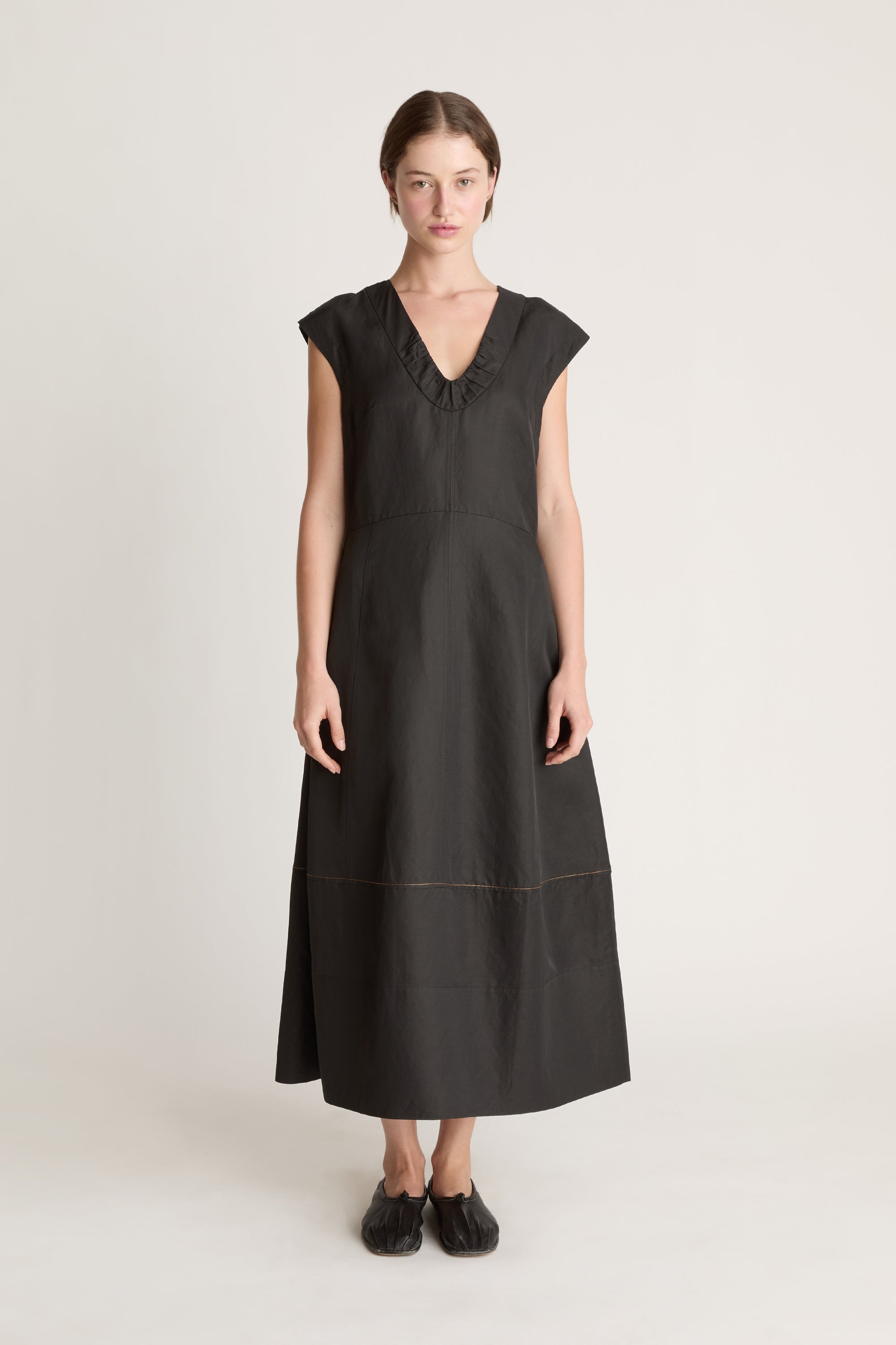Woman wearing a black  v neck dress on a white background
