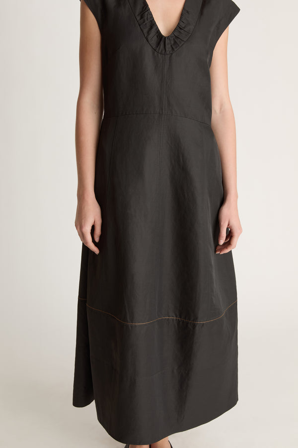 Woman wearing a black  v neck dress on a white background