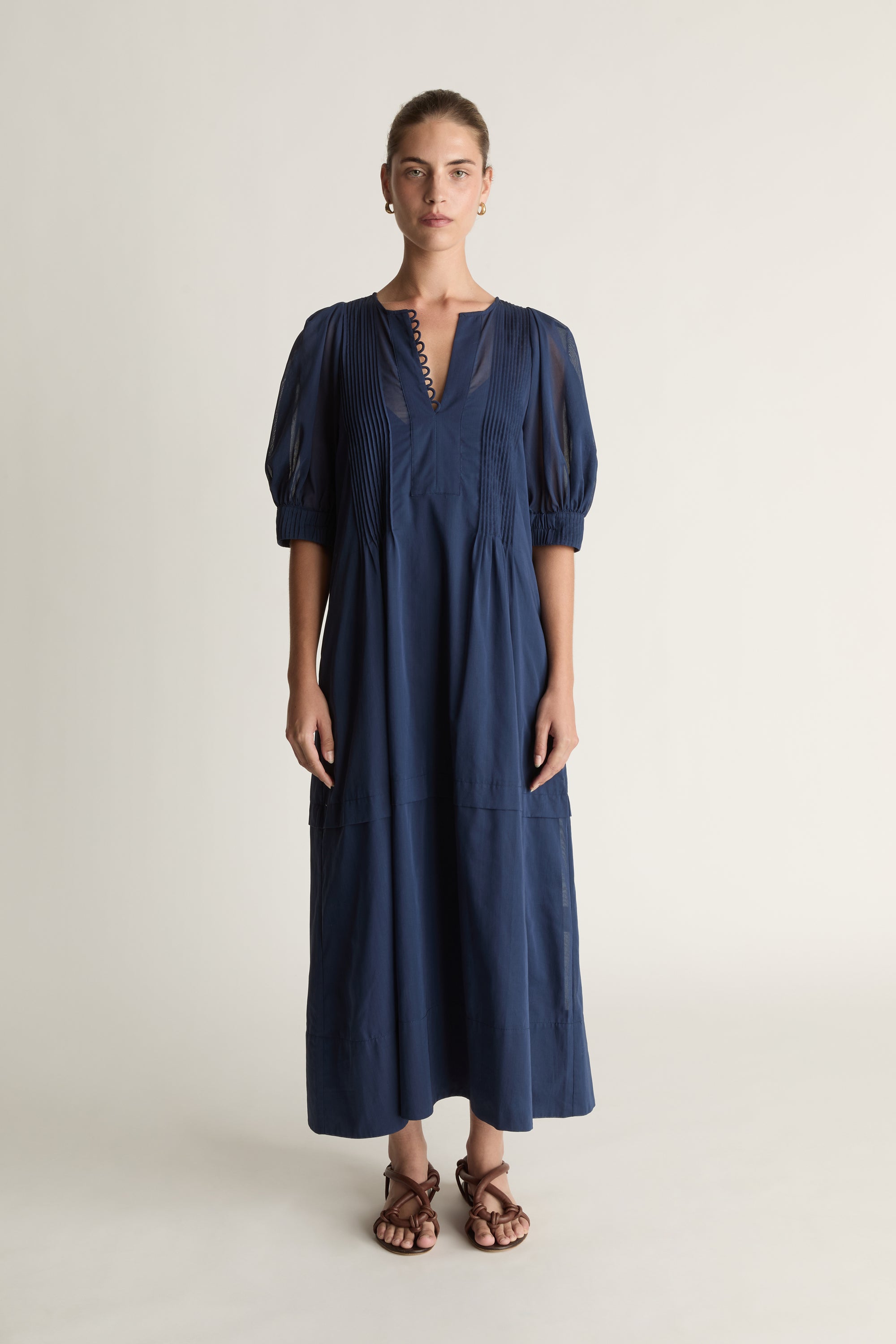Woman wearing a navy blue dress on a plain background