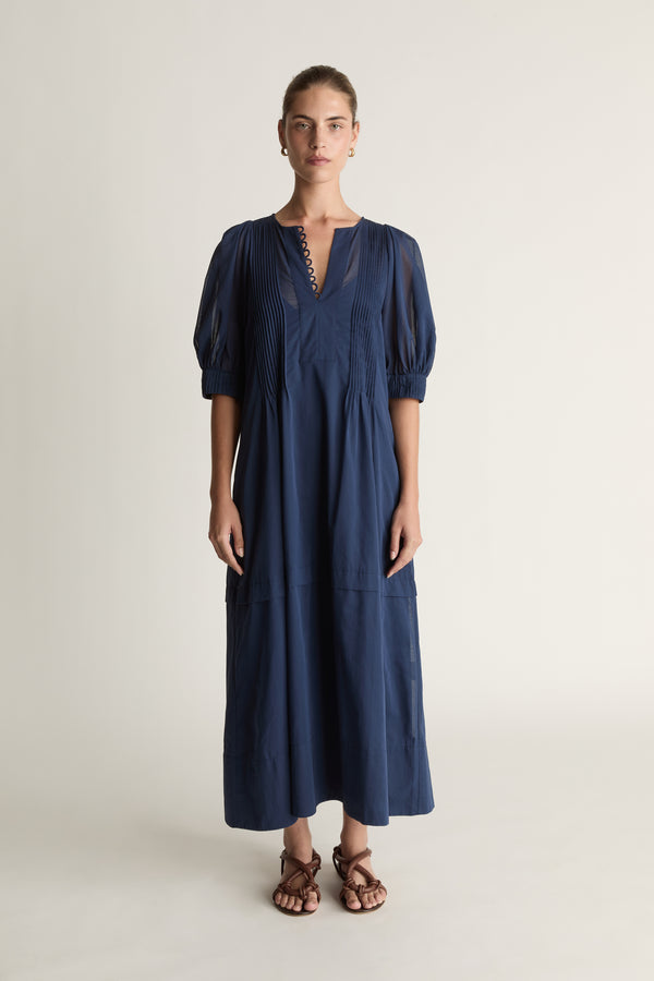 Woman wearing a navy blue dress on a plain background