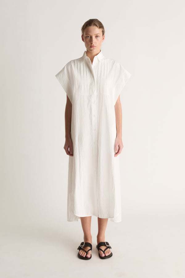 Front view of a white midi shirt dress with wide cap sleeves, a pin-tucked bib and button front.
