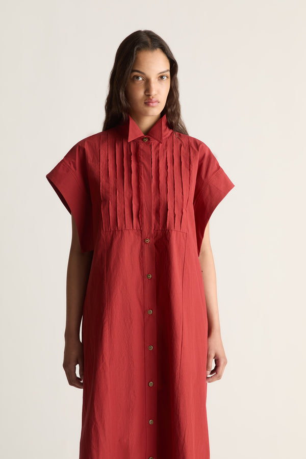 Close-up of a red shirt dress with pointed collar, pleated bib and button front