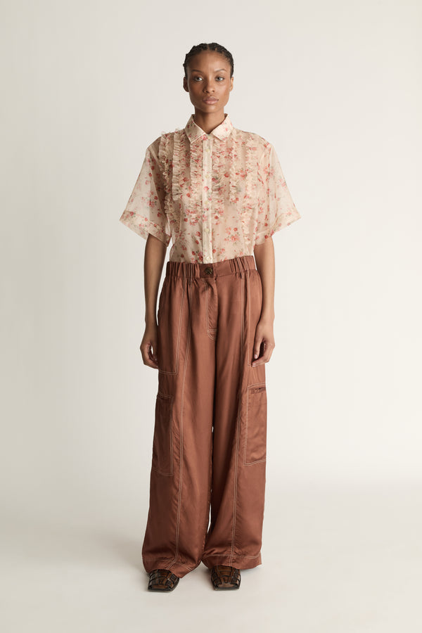 Person wearing a floral blouse and brown pants on a white background