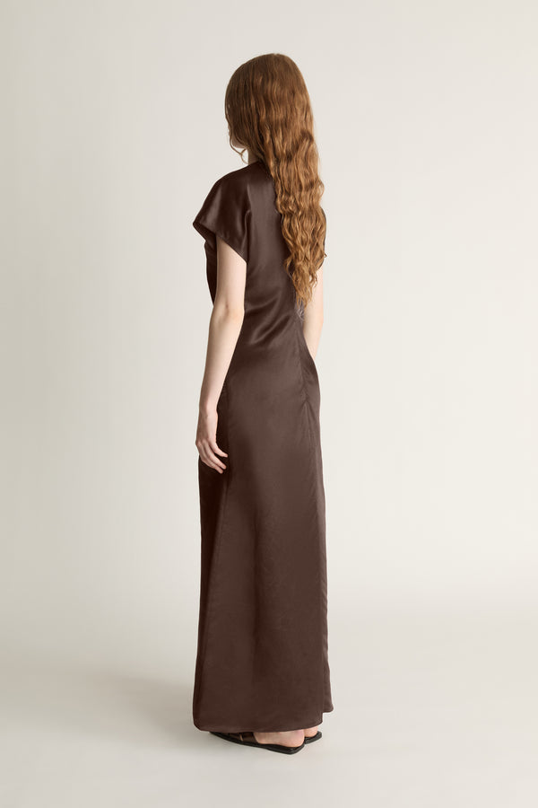 Woman wearing a brown dress against a plain background