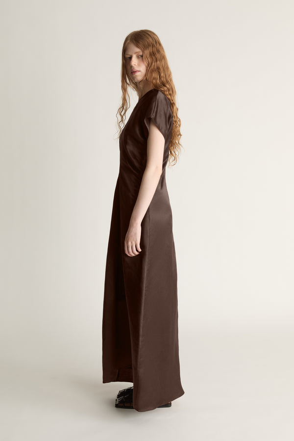Woman wearing a brown dress against a plain background