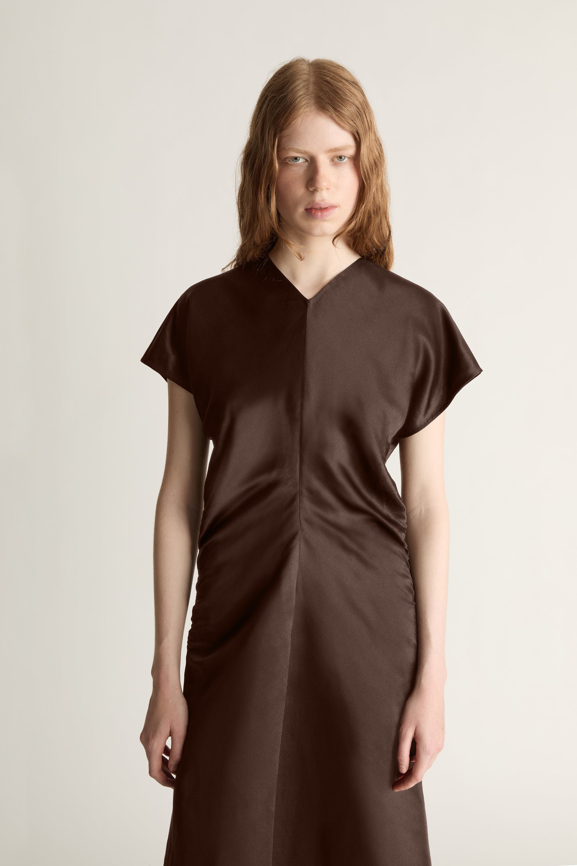 Woman wearing a brown dress against a plain background