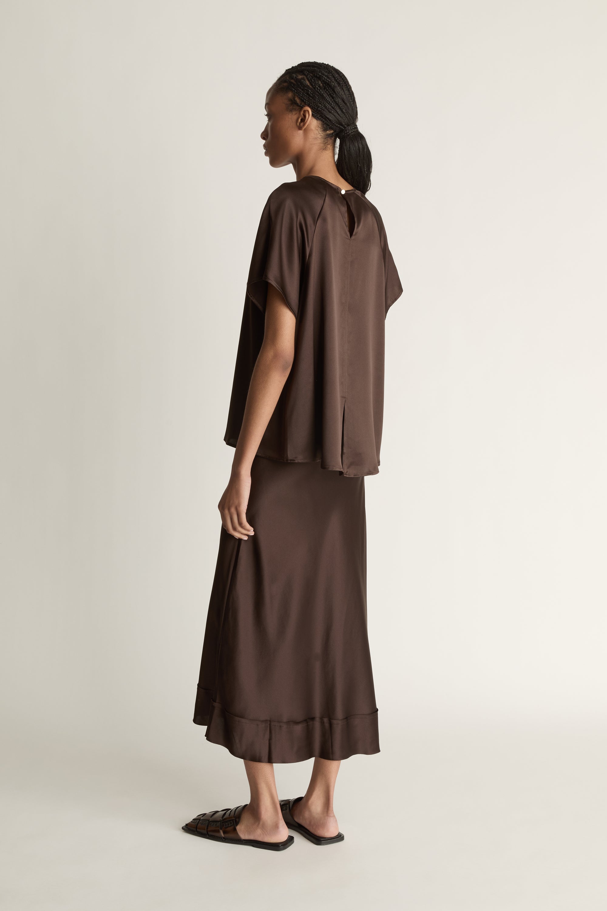 Woman wearing a brown outfit on a plain background