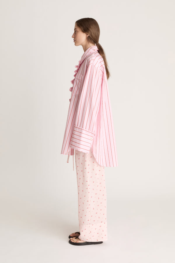 Woman wearing a pink striped shirt with floral pink pants on a white background