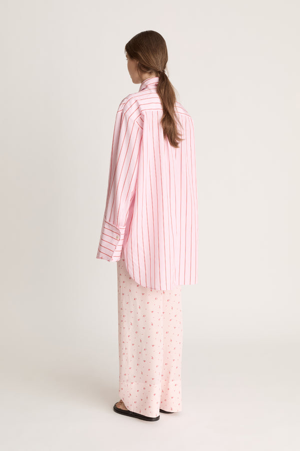 Woman wearing a pink striped shirt and pink floral pants on a white background
